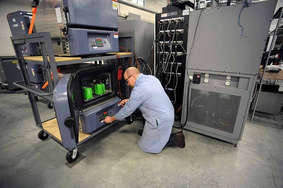 Technician working with battery testing equipment racks